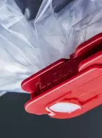 Detailaufnahme einer roten Lugaia SafeSeal-Klemme, die eine Einweg-Containment-Folie sicher verschließt – für staubdichte, kontaminationsfreie Anwendungen in der Pharmaindustrie.