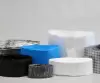 Stack of folded liner foils in various colors and materials, neatly arranged. Visible variants include black, transparent, white, blue, and metallized — commonly used in pharmaceutical or chemical containment.