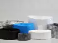 Stack of folded liner foils in various colors and materials, neatly arranged. Visible variants include black, transparent, white, blue, and metallized — commonly used in pharmaceutical or chemical containment.
