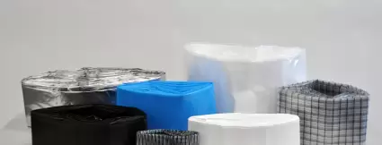 Mehrere gefaltete Liner-Folien in unterschiedlichen Farben und Materialien, sauber aufeinandergestapelt. Sichtbar sind Varianten in Schwarz, Transparent, Weiß, Blau und metallisiert – typisch für pharmazeutische oder chemische Anwendungen.