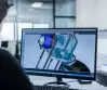 Ein Mitarbeiter arbeitet an einem CAD-Modell eines Containment-Systems am Computerbildschirm – technische Konstruktion mit Isolator und Behälter in 3D.