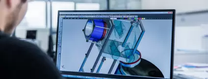 An employee working on a CAD model of a containment system on a computer screen – technical 3D design featuring an isolator and container.