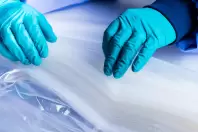 Close-up of gloved hands carefully folding film material in cleanroom production – preparing single-use containment systems at Lugaia.